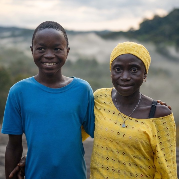 Lucia Mansaray and her son, Beshey. Lucia is a member of Fairtrade cocoa co-operative called Ngoleagorbu in Sierra Leone. Lucia is a cocoa farmer and lives in a community on the edge of the Gola rainforest, sharing her forest home with chimpanzees, hundreds of rare bird species and the elusive pygmy hippo, of which only 3,000 remain. In 2019, Lucia and hundreds of other cocoa farmers here came together through Fairtrade to form the Ngoleagorbu Union of Cocoa farmers, where passions for social and environmental justice run deep. Lucia is passionate and hopeful about what the future holds for her family and Ngoleagorbu, and her drive for change has led her to be chairperson of the Fairtrade Premium Committee.