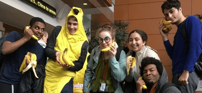 A totally bananas group of Concordia students rep the Fair Trade Campus. One on them is wearing a banana costume while the other ones are holding bananas like phones.